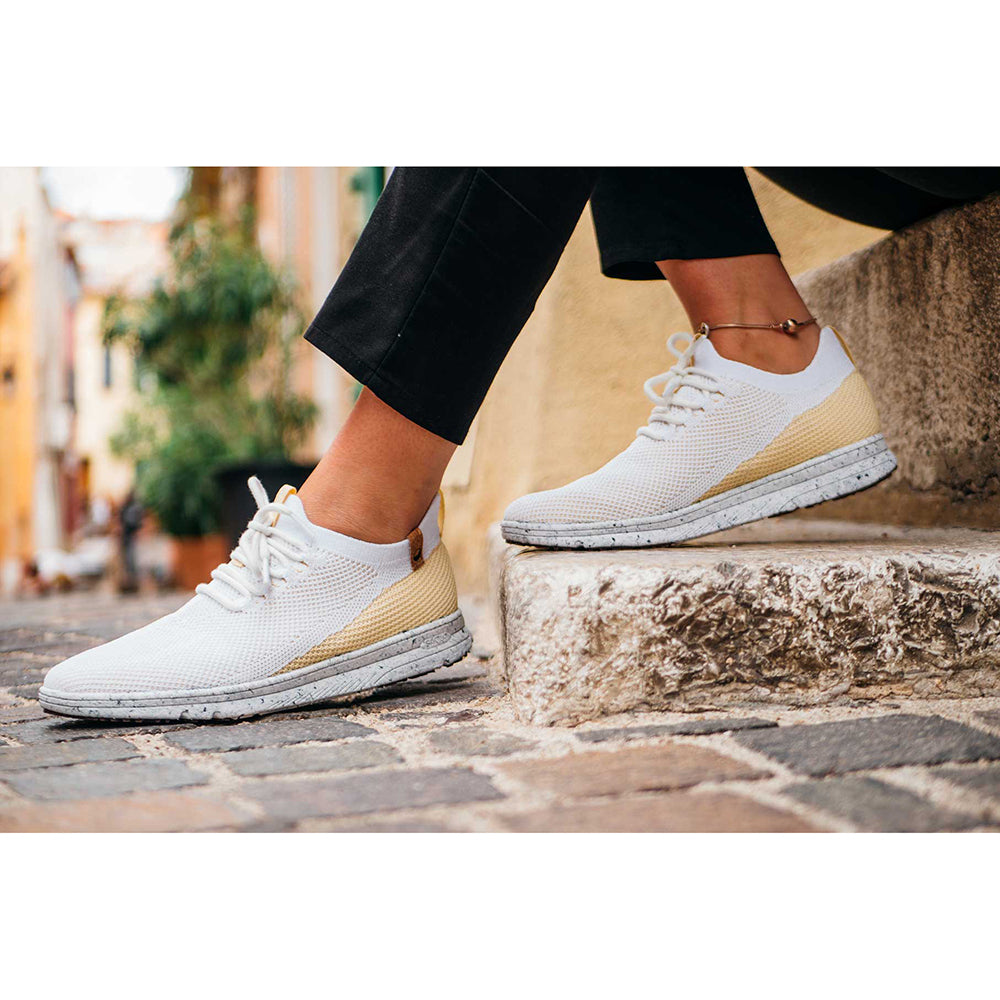 Saola Tsavo. Women's lightweight vegan sneaker in white and yellow knit made from plastic. Model view.
