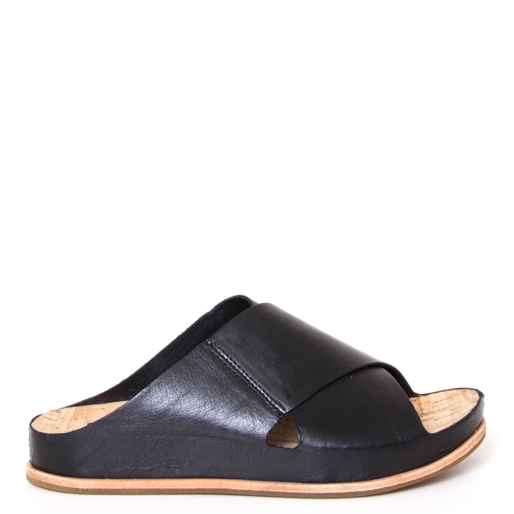 Kork-Ease Tutsi Cross-Band. Women's slide sandals in black criss-cross leather straps. Cushioned anatomical cork footbed for comfort and arch support. 1-inch flat heel. Side view.